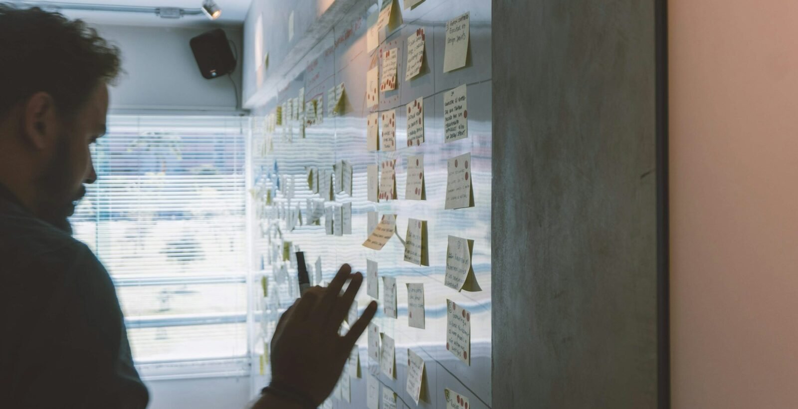 male putting sticky notes on wall